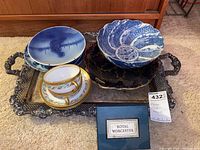 Photo showing a silver plated serving tray holding two decorative blue and white china plates, a serving bowl, two tea cups with saucers, and a Royal Worcester egg coddler box.