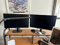 Two monitors side by side on wooden desk showing overall condition
