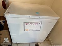 Front and top view of the white chest freezer showing exterior condition and label.