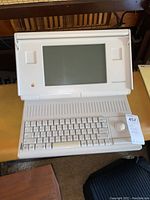 Front view of Macintosh Portable open showing keyboard, trackball and CRT display with case visible.