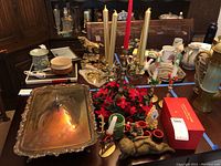 Overview photo showing brass 5-arm candelabra with candles, silver-plated serving tray, assorted cherub figurines, candles, and boxed Cathedrals of the World ornaments.