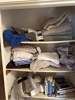 Shelves with folded blankets and sheets, a folded blue blanket, and boxed Snuggie.