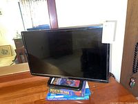 Front view of the Element flat screen TV on a dresser supported by books, showing the screen and brand logo.