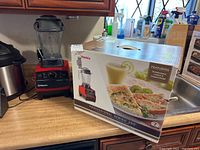 Blender and original box on countertop next to pot and sink