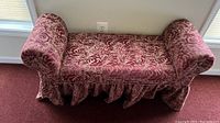 Front view of maroon damask bed bench showing upholstered seat, rolled arms, and skirted base.
