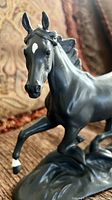 Close-up front view of black bisque porcelain horse figurine showing detailed face and white markings on forehead and front hoof.