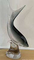 Full side view of the blown glass fish sculpture showing the elegant curve and gradient from clear to black glass.