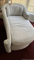 Full view of off white chaise lounger sofa showing curved backrest, armrest, and cushioned back pillow