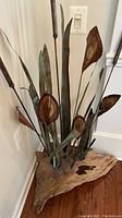 Photo showing the large faux flower decor with driftwood base, detailed view of the leaves, flower heads, and cattails.