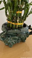 Close-up of bamboo stalks bound with gold bands in green elephant planter