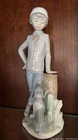 Front and side angle of the glazed porcelain figurine featuring the boy and dog, highlighting detailed expressions and clothing.