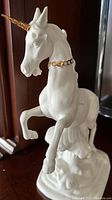 Front-side view of the white porcelain unicorn with gold horn and collar, showing pose and detailing.