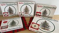 Boxes of Spode Christmas Tree pattern serving pieces, including square buffet dish and oval vegetable baker, showing front of packaging and tree design.