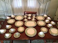Overview of all pieces arranged on dining table showing plates, cups, saucers, platter and compote bowl