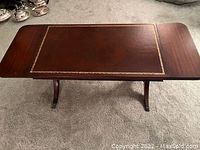 Image showing the full view of the drop-leaf coffee table, top extended, highlighting the leather inlay and brass border.