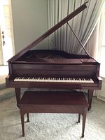 Front view of open-lid baby grand piano with matching bench