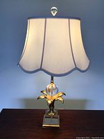 Front view of one lamp showing shade, glass orb, palm leaf motif and mirrored base