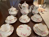 Full set displayed on table: teapot, sugar bowl, creamer, 4 cups, 4 saucers showing design and condition