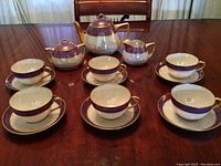 Full tea set arranged on table showing cups, saucers, teapot, sugar bowl and creamer