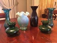 View of all six vases together showing different styles, colors, and shapes on a table.