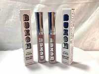 Two tubes of Buxom Full-On Lip Cream standing upright next to their original white boxes, showing the brand and packaging details.