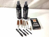 Two 118ml M-Pro 7 cleaner bottles alongside four different sized gun cleaning brushes and a Hoppe's red rod accessories box.