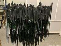 Full view of a large collection of mostly Ping branded golf shafts with various Golf Pride grips attached.