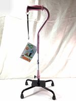 Front view of pink Hugo walking cane with ergonomic offset handle, cushioned grip, four-point black base, and attached wrist strap.