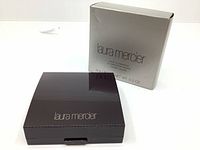 Compact powder case and original box with Laura Mercier branding on a white background.