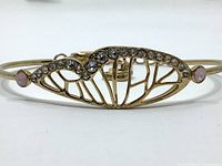 Close up view of gold plated butterfly wing bangle showing crystal embellishments and pink crystal accents.