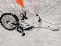 Side view of assembled white trail-a-bike frame with rear wheel and hitch arms