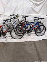 Three bicycles shown side by side with visible wear, parts and cables need repair or replacement.