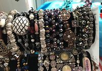 Bracelets displayed on black velvet stand showing variety of bead styles, charms, and decorative elements in close-up
