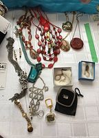 Overview of costume jewelry laid out on a surface showing necklaces, rings, earrings, keychain, and pocket mirror