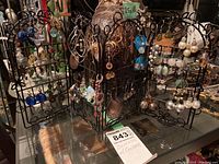 Black metal jewelry stand holding multiple costume earrings with semi-precious stones and beads.