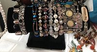 Front view of nine costume jewelry bracelets on black velvet display stand