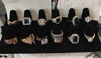 12 costume jewelry rings with synthetic stones displayed on a black velvet holder