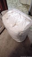 Duvet compressed and packed inside a large clear plastic bag, white in color, with a label attached.