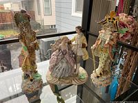 Photo showing the three Italian ceramic figurines on a glass shelf with a window behind them.