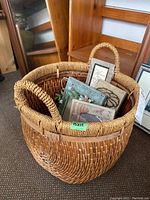 Large woven basket containing several special occasion decorative picture frames in various pastel colors and floral/ribbon designs.