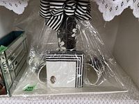 Set of mugs, tray, and chopsticks wrapped in plastic, displayed with lace doilies in the background.