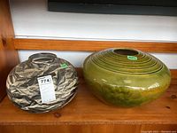View of two large artisan pottery vases on wooden shelf, showing overall shape and pattern of each