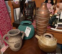 Four vases displayed on a wooden surface, showing variety in material and design.