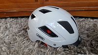 Side view of white Abus Hyban 2.0 bicycle helmet showing ventilation design and Abus brand logo.