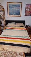 Full photo of bed with Hudson Bay blanket laid out showing signature colored stripes and overall condition.
