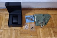 Contents of lot displayed including Hamilton watch box, necklaces, pendants, and pouch on wood floor