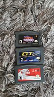 Three Nintendo Gameboy Advance game cartridges laid on carpet, showing labels 'Band Hero', 'GT Advance 2 Rally Racing', and 'Starsky & Hutch'.