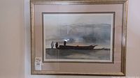Full view of the framed artwork showing the three silhouetted figures next to a boat in muted colors and misty background.