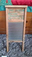 Front view of 'The Junior' washboard showing wood frame, metal scrubbing surface, and green branding text