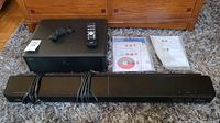 Yamaha soundbar and subwoofer with remote control, power cord, manuals, and installation CD arranged on carpet.